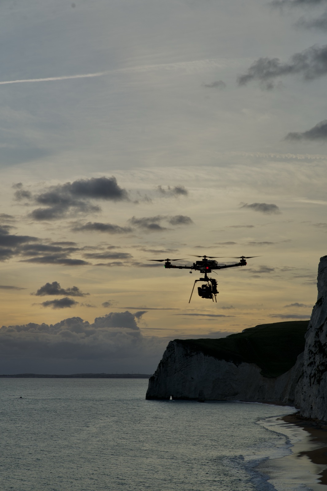 Heavy-lift cinema drone over chalk cliffs at dusk