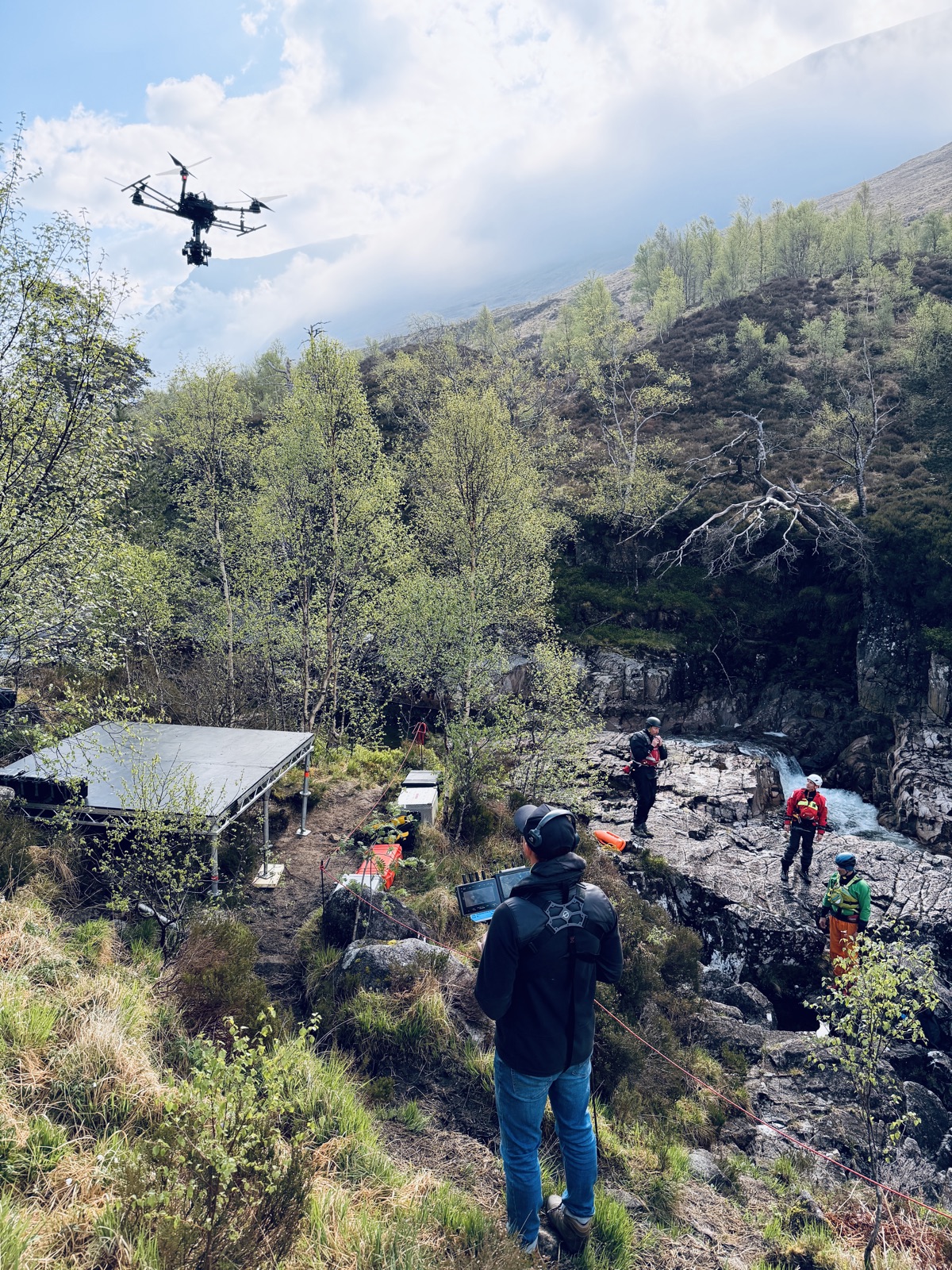 Heavy-lift drone over a Highland river gorge with safety crew