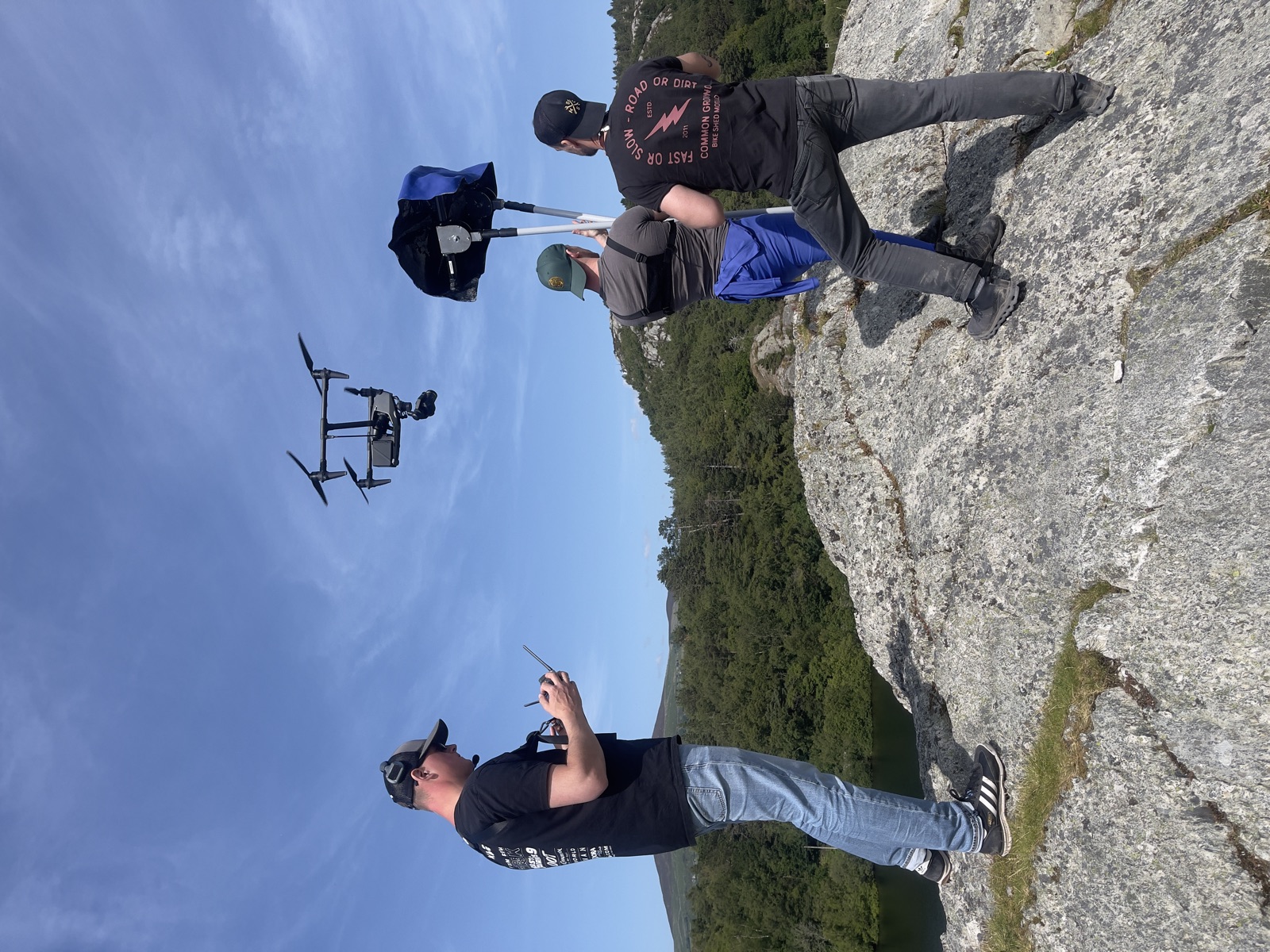 Crew flying a DJI Inspire over a lake at a clifftop
